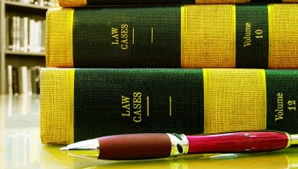 Photo of Law books stacked on desk with an ink pen ready to write